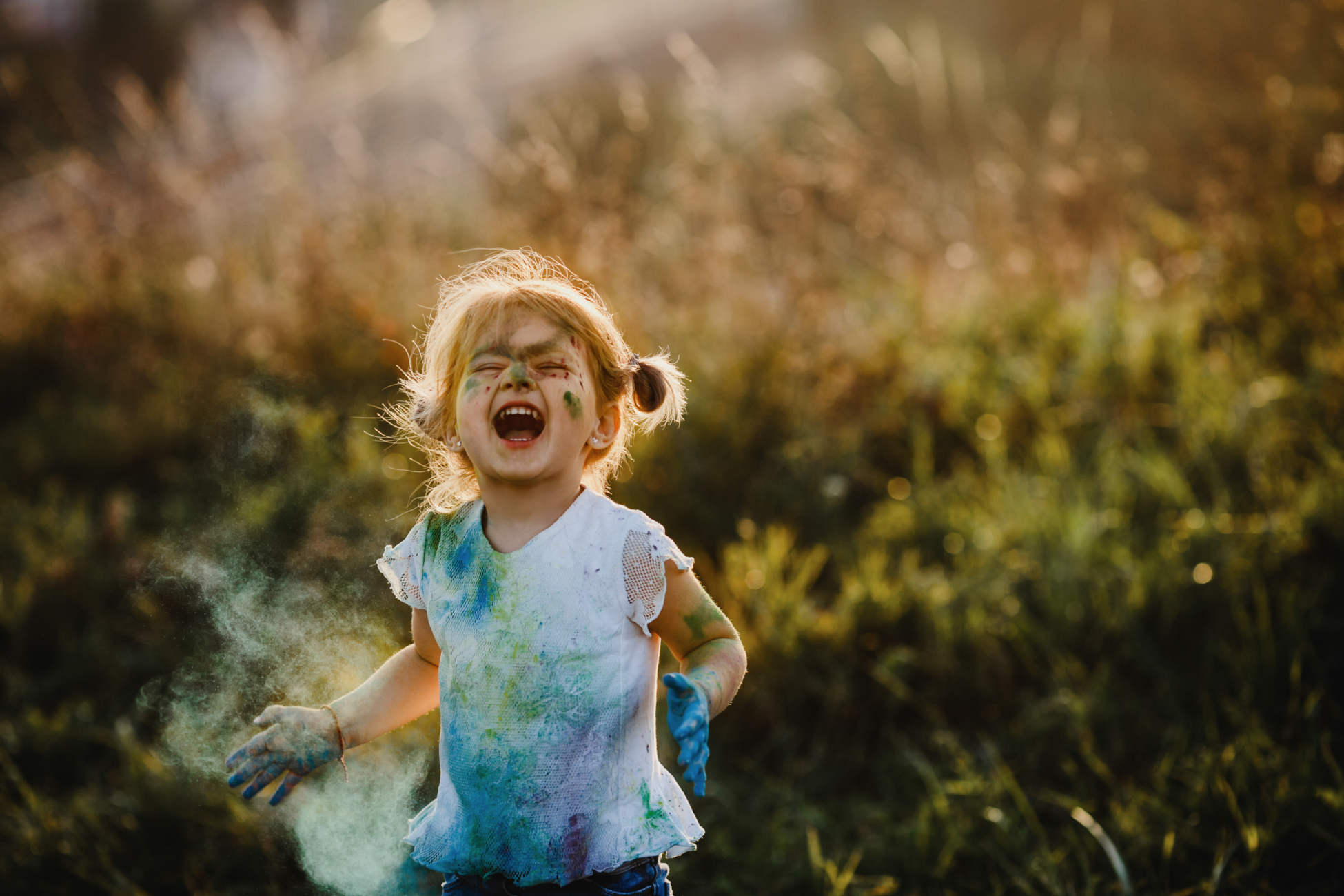 Charming little girl with white shirt covered with different paints